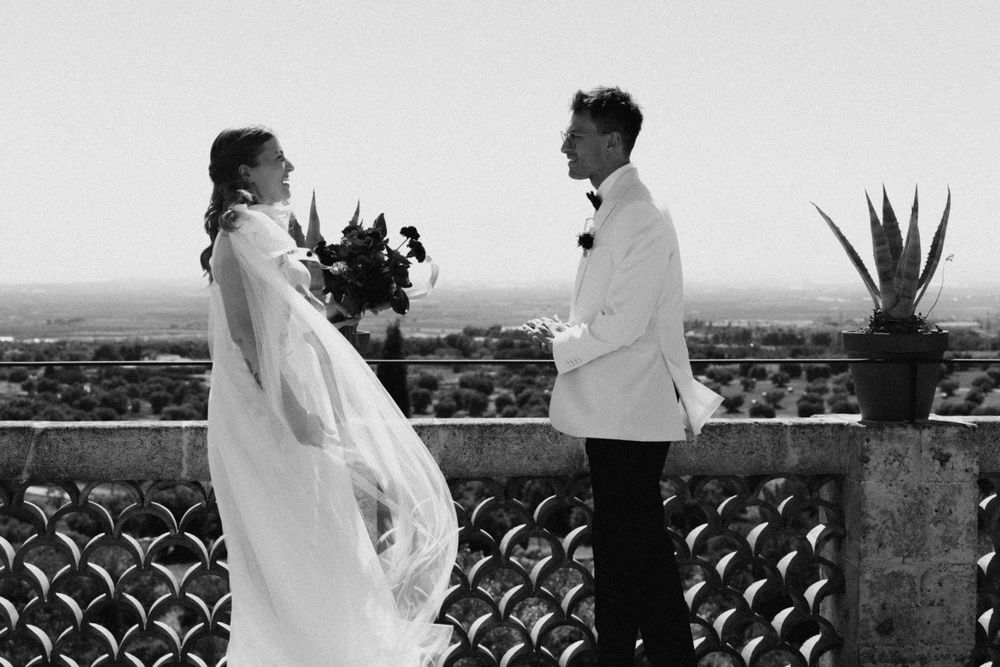 Black and white photo of a bride and groom exchanging vows on a scenic terrace with a panoramic view.