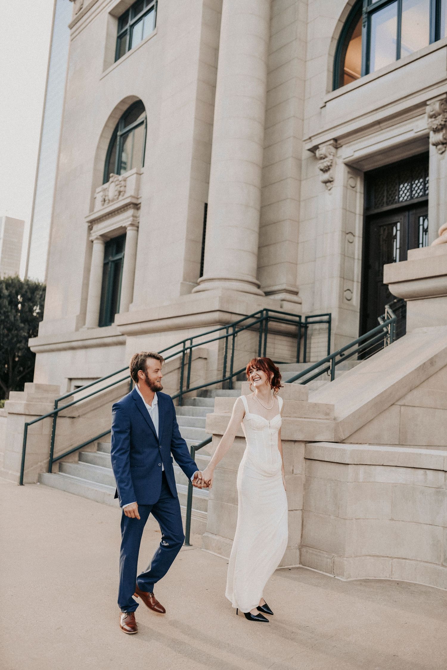 Dallas engagement couple holding hands in front of historic limestone architecture