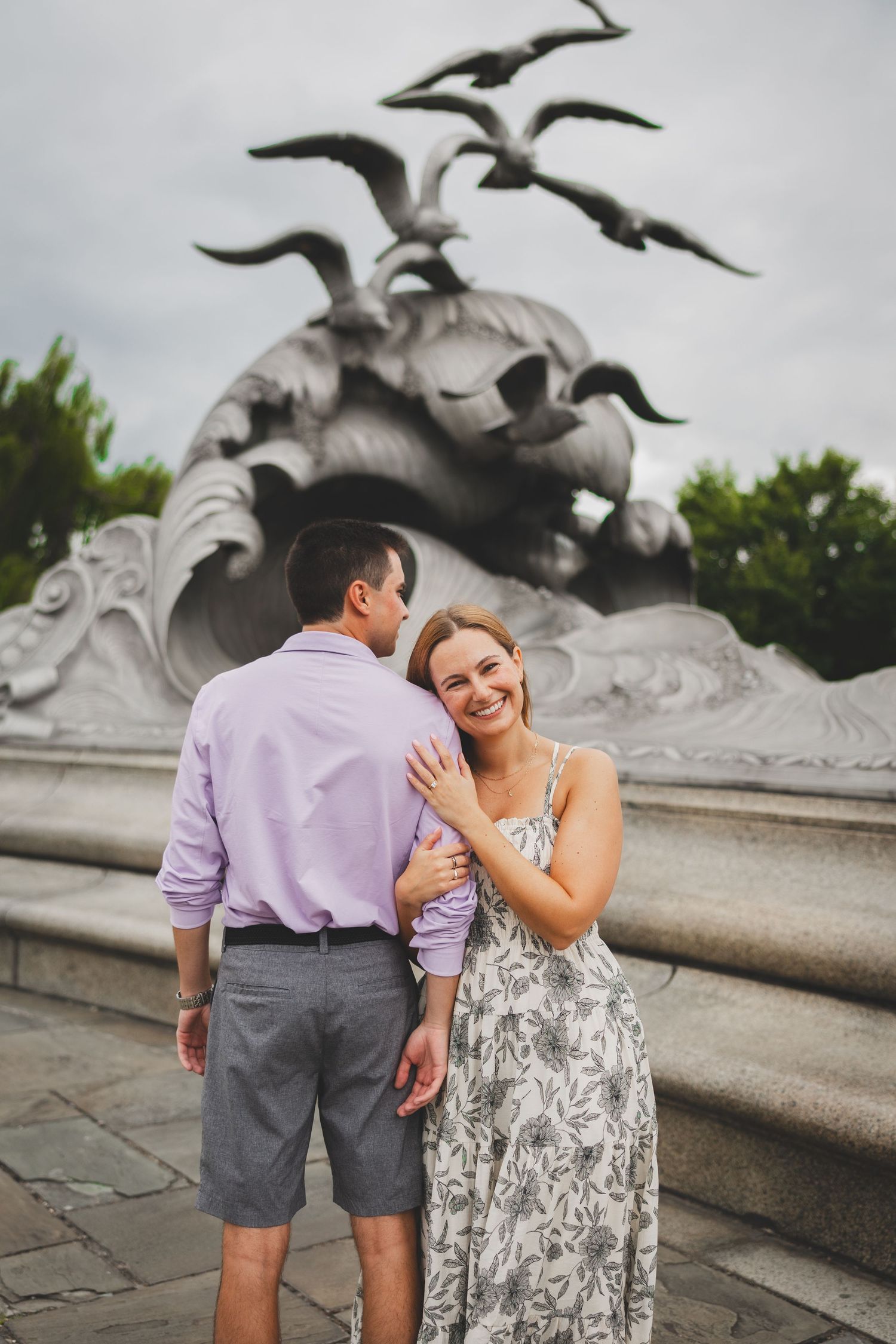 Couple embracing and smiling in front of the navy merchant marine memorial in dc
