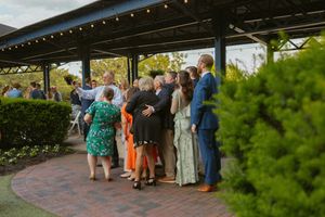 Guests mingling under an outdoor pavilion at a garden wedding reception during golden hour.
