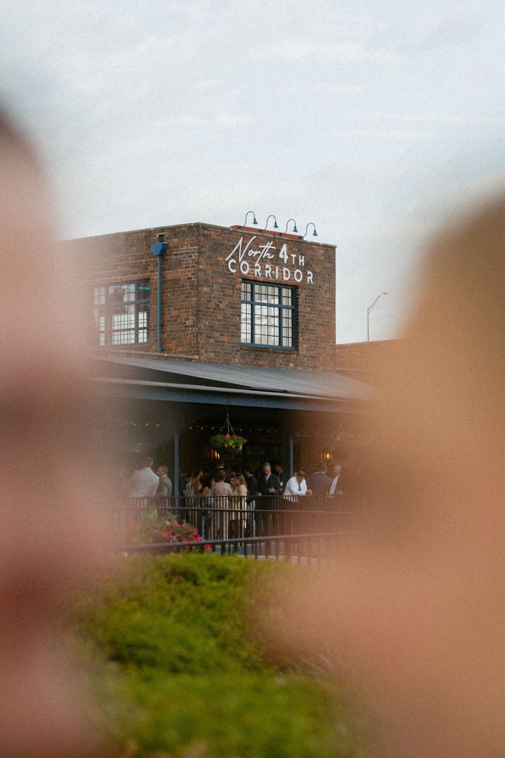 North 6th Corridor brick venue building with guests gathered on outdoor patio at dusk wedding reception.