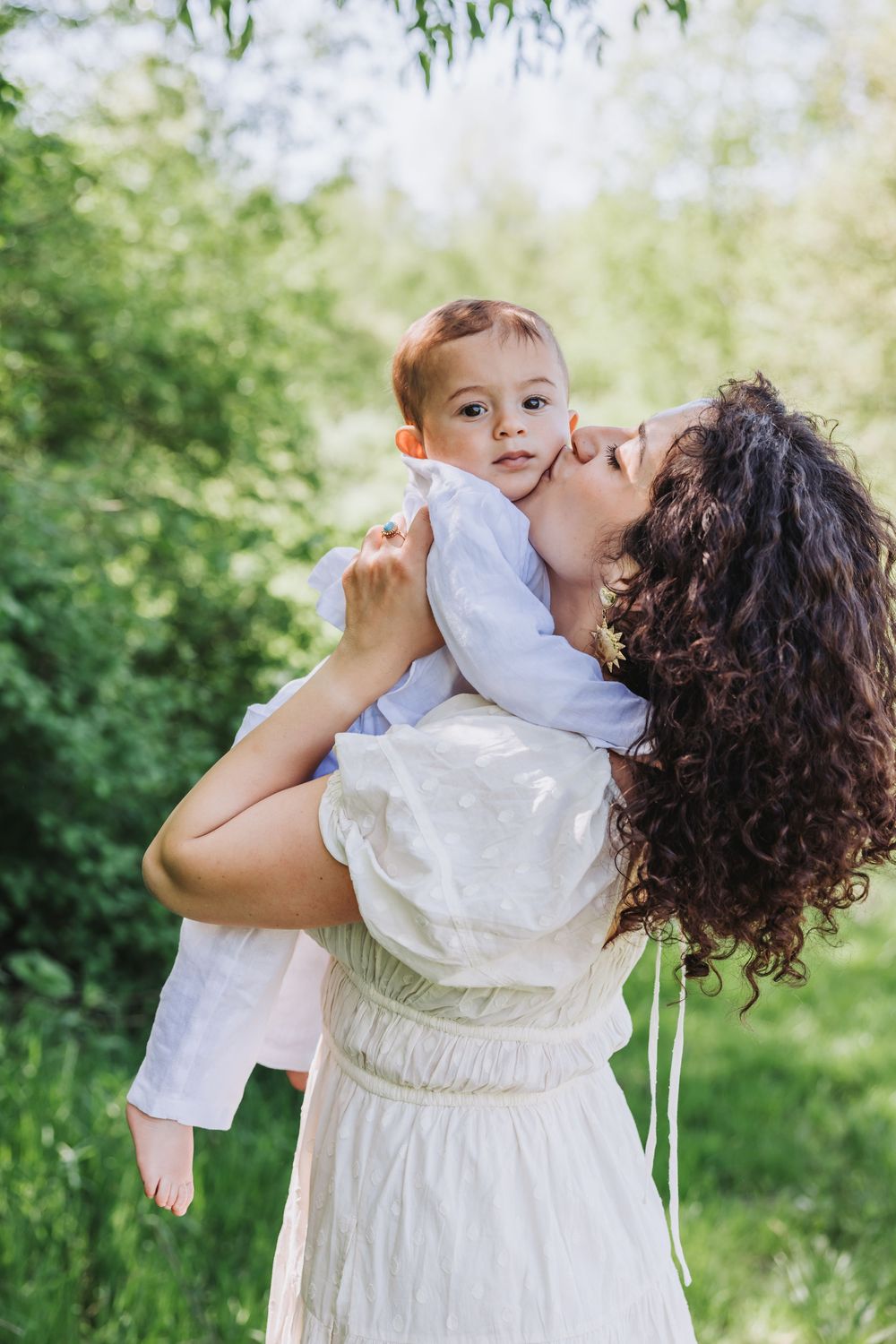 Candid photo of mother lifting her baby and giving him a kiss during a natural mommy and me photoshoot.