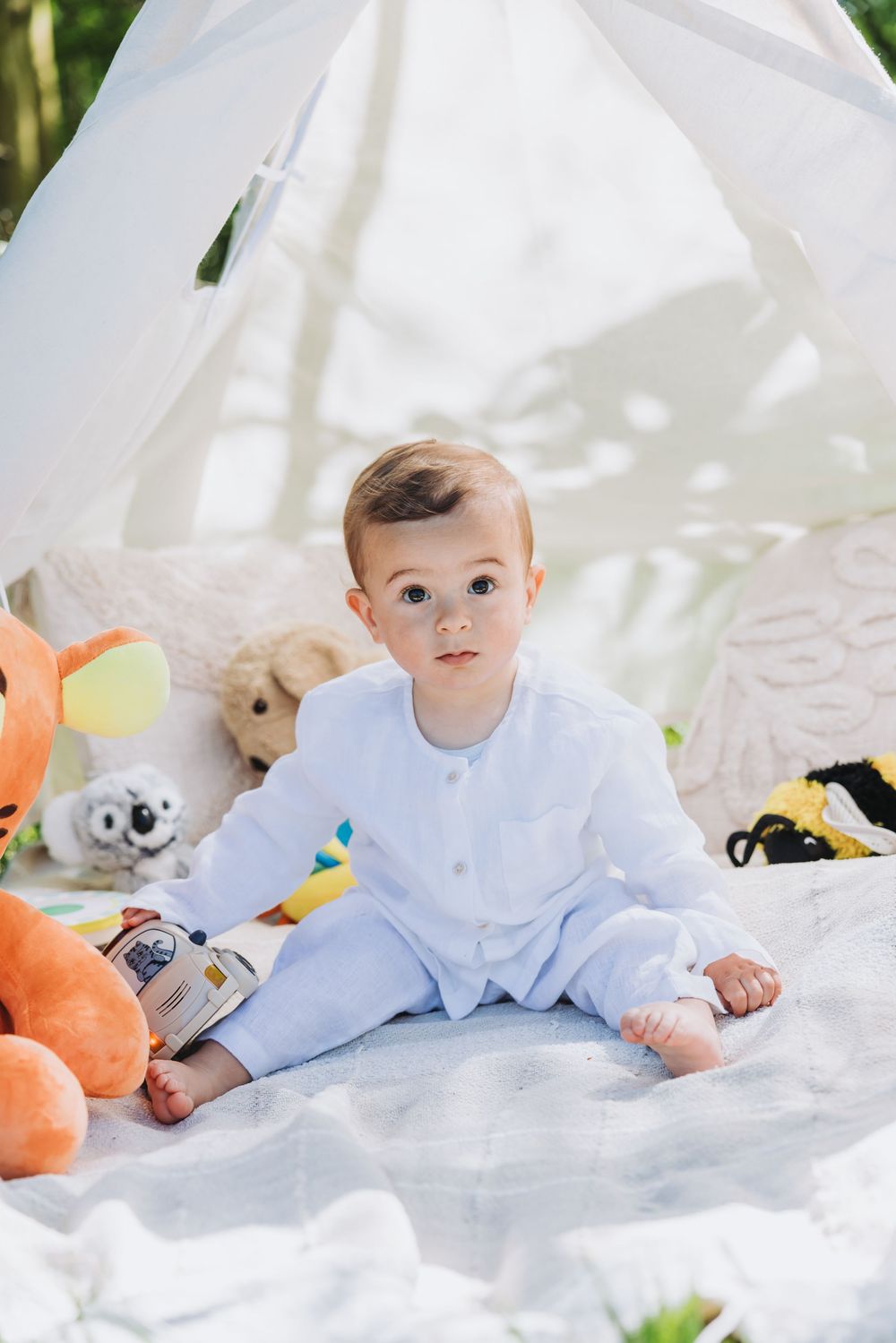 Lifestyle portrait of baby boy on his first birthday with boho decor - tepee tent, blankets and colorful toys.
