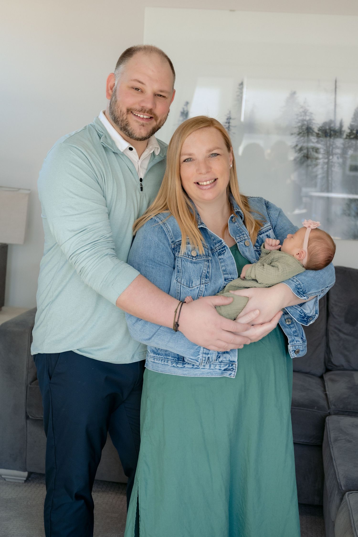 parents smile at the camera while holding newborn baby girl during in home lifestyle newborn session in lake elmo, mn