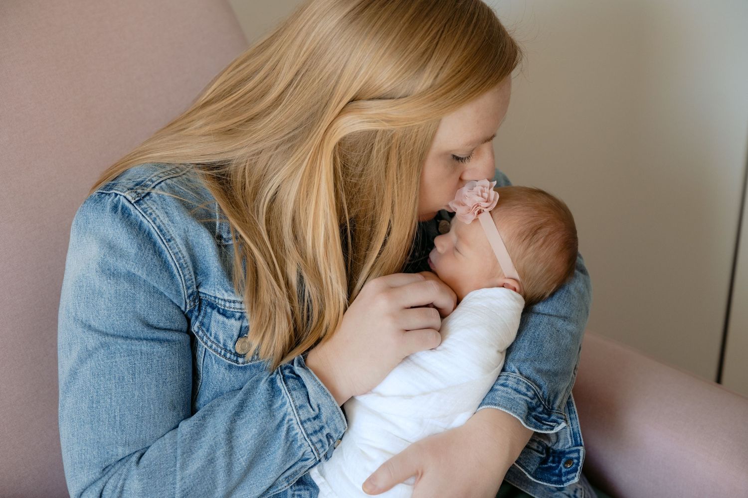 mom kissing swaddled newborn in nursery during in home lifestyle newborn session in lake elmo, mn
