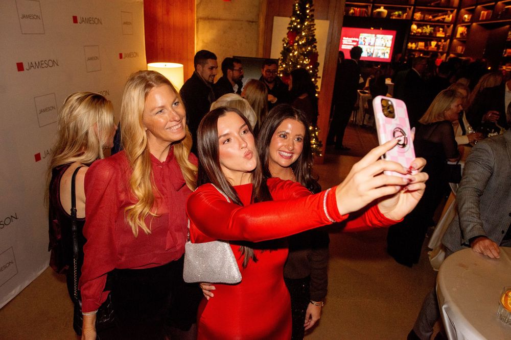 Women taking a selfie at a festive Jameson whiskey holiday party event.