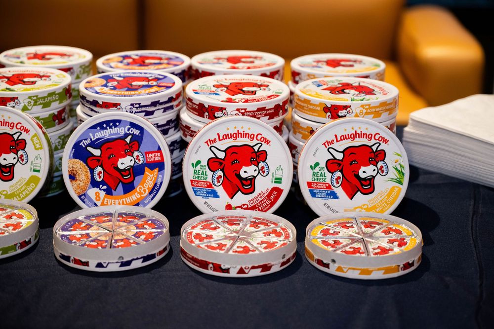 Stacked rounds of The Laughing Cow cheese boxes displayed on a table at an event.