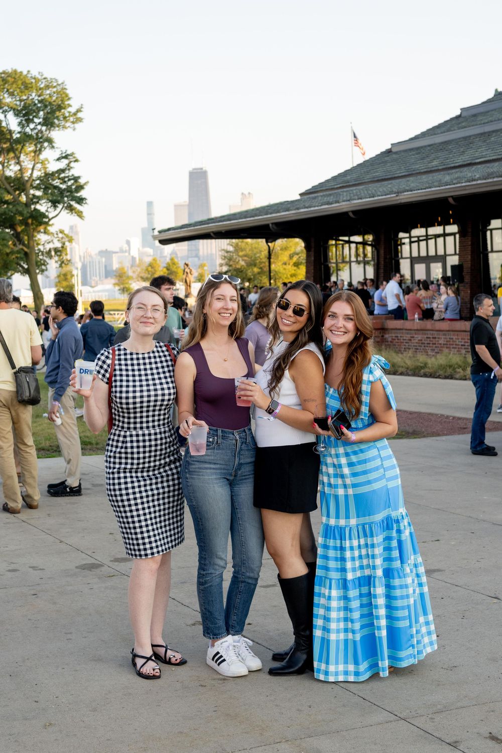 Four women posing together outdoors at a waterfront event with city skyline in background.