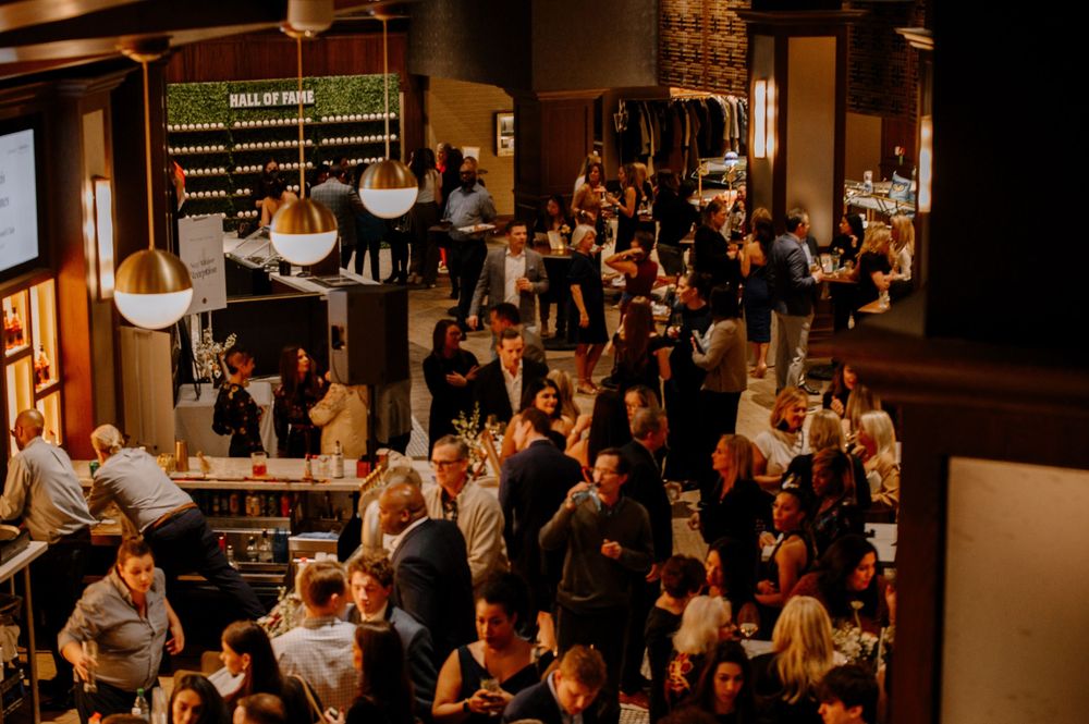 Aerial view of a crowded upscale networking event with guests mingling in a warmly lit venue.