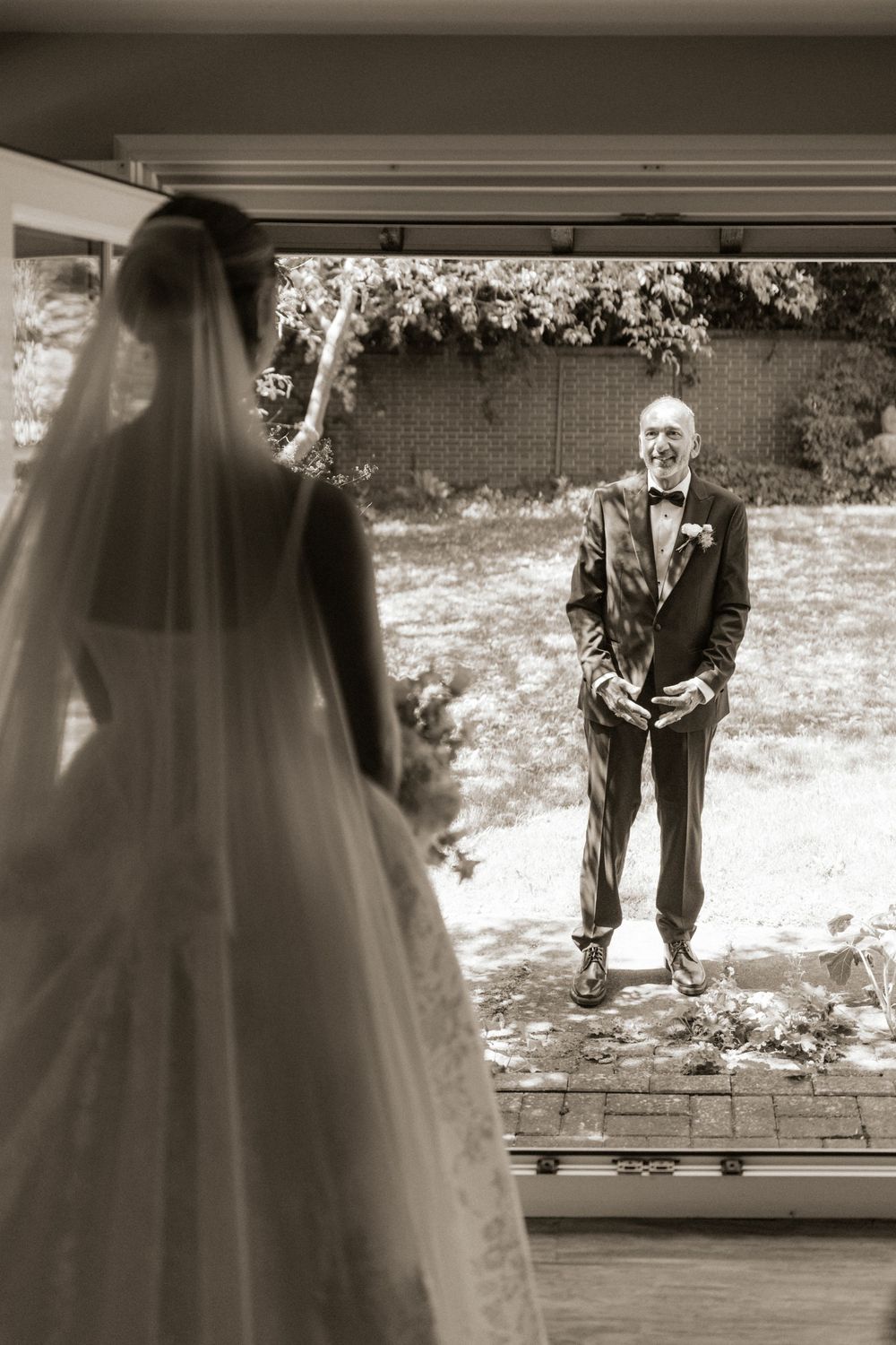 Black and white photo of a father emotionally seeing his bride daughter for the first time on her wedding day.