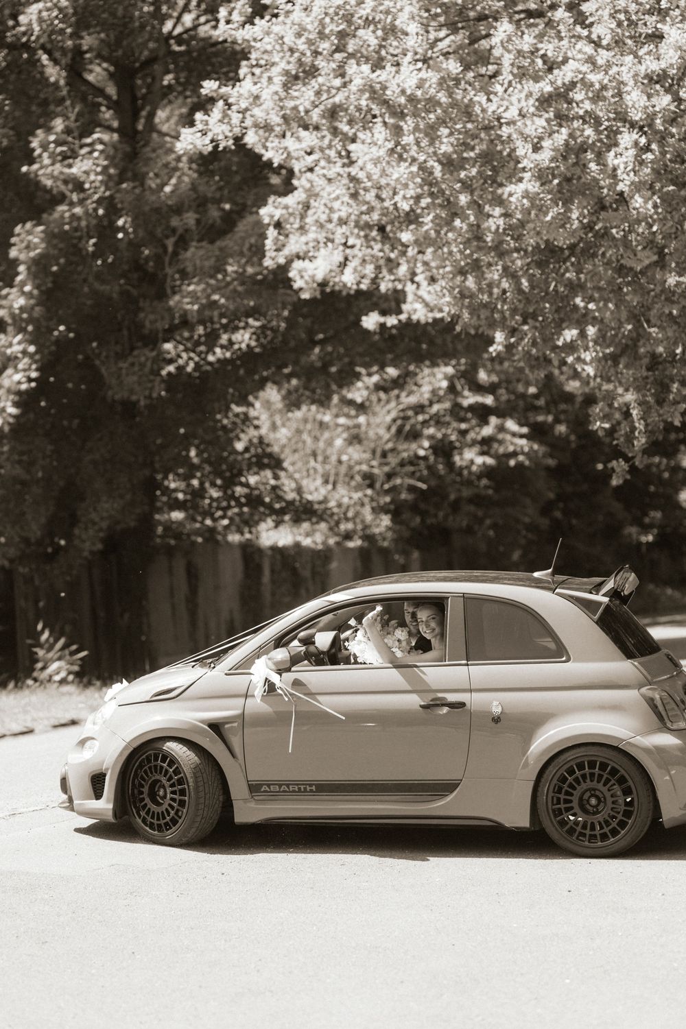 Fiat Abarth 500 modified sports car parked on a road surrounded by trees in a sepia-toned photograph.