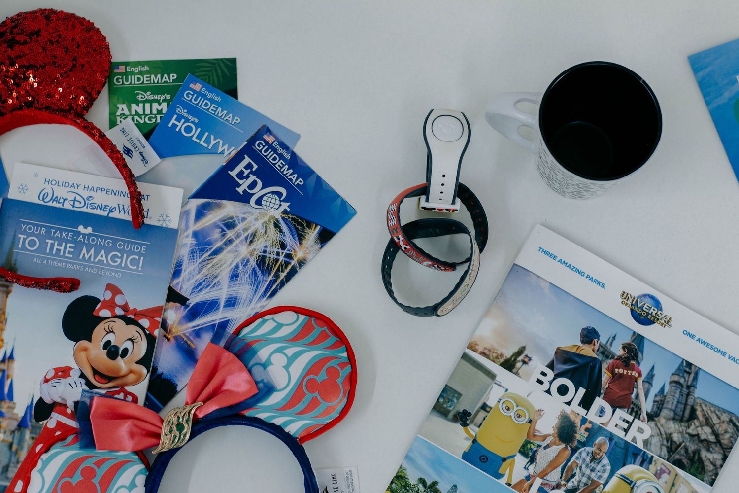Disney World vacation essentials flat lay with Mickey ears, park maps, MagicBand, and Lonely Planet guidebook.