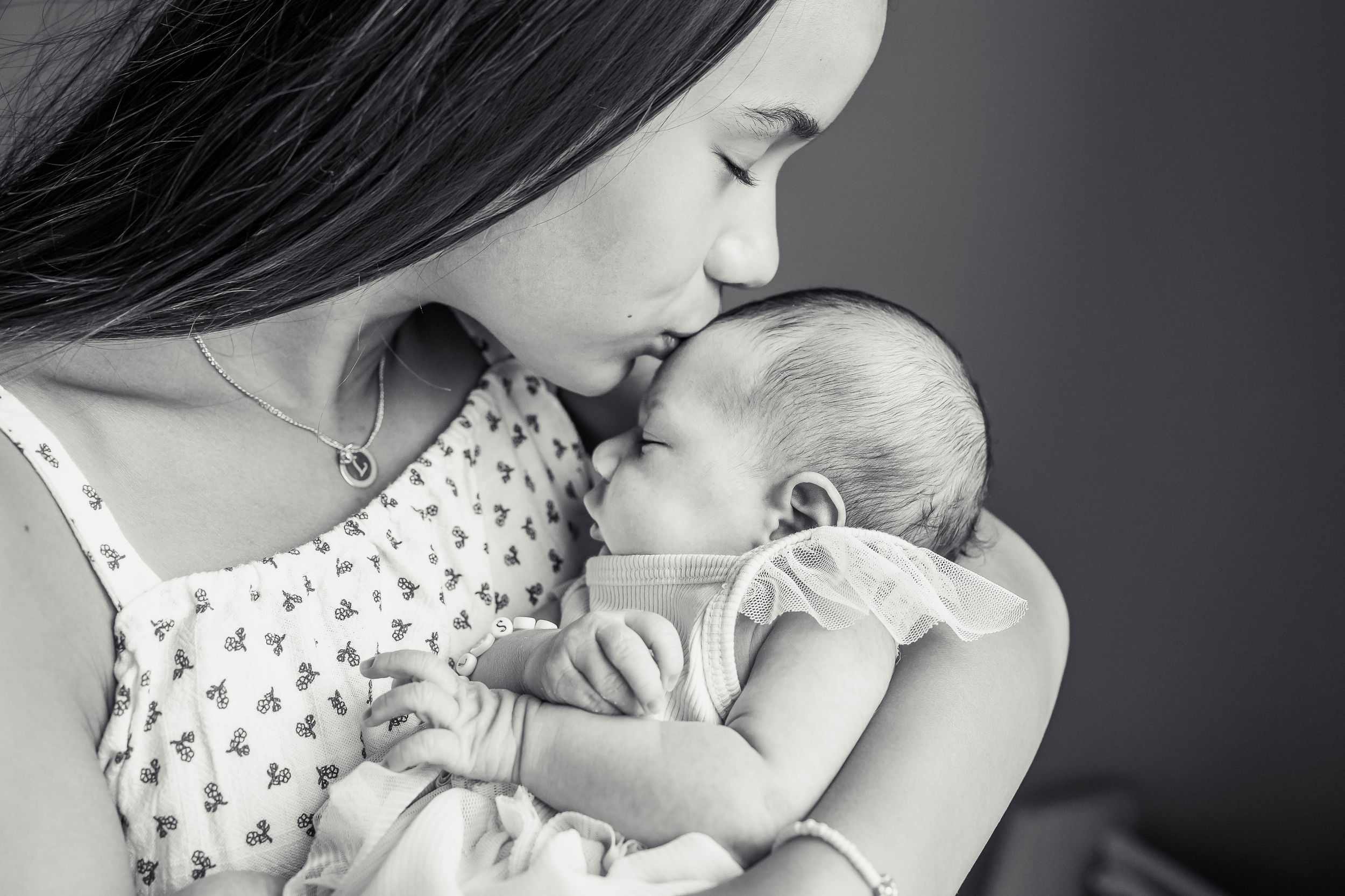 Sister kissing newborn baby.
