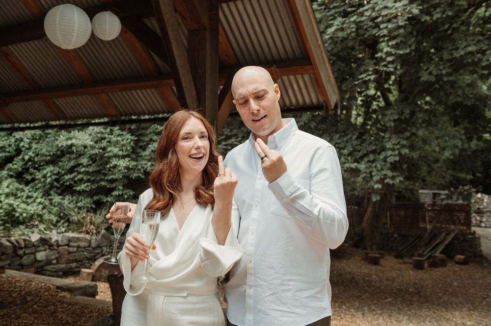 Happy bride and groom toast with champagne glasses at outdoor wedding reception.