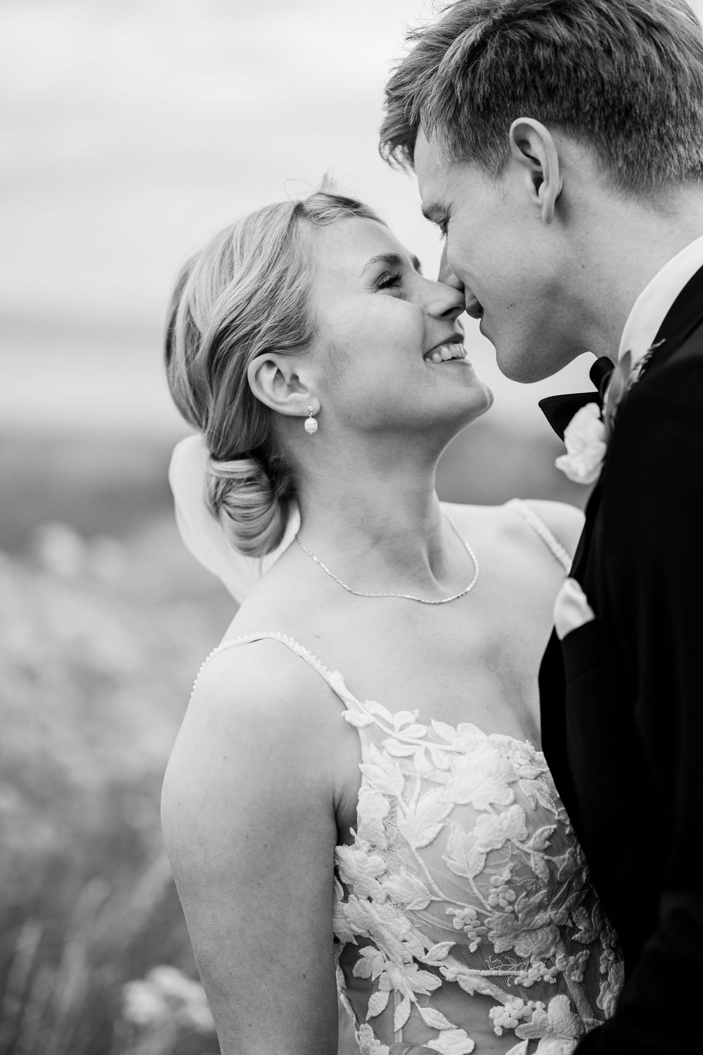 Black and white close-up of smiling bride and groom sharing a tender nose-to-nose moment on their wedding day.