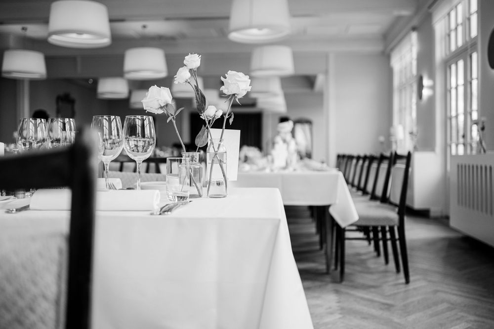 Elegant black and white restaurant interior with white tablecloths, wine glasses, and floral centerpieces.