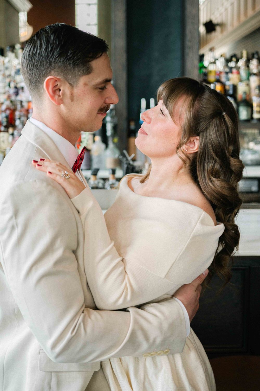 A tender moment captured between a couple in formal attire at an elegant bar setting.