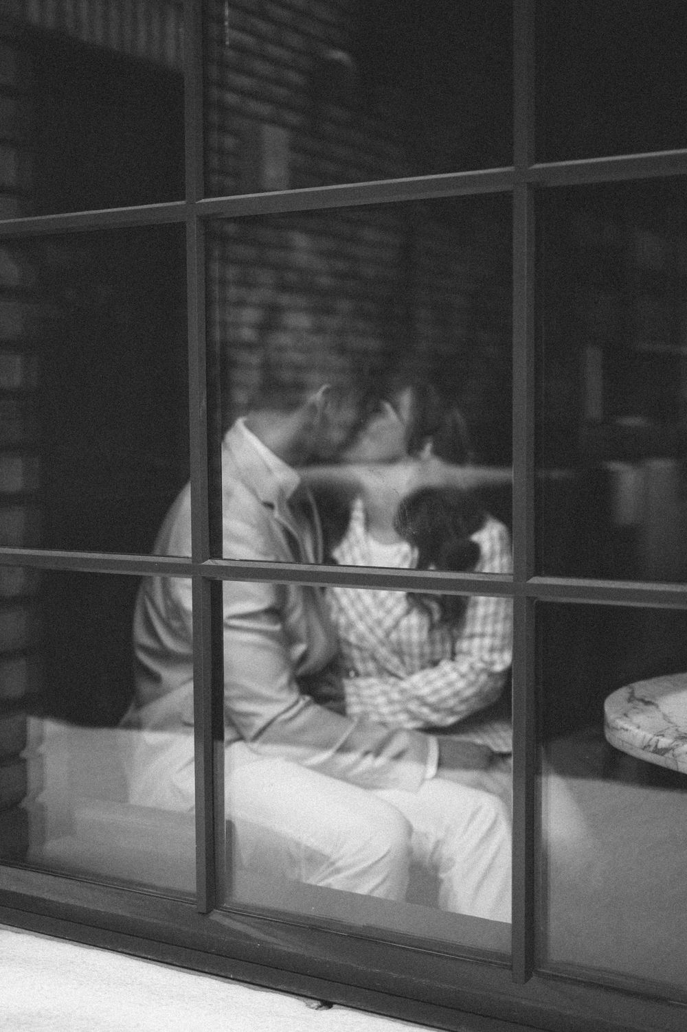 Artistic black and white photo of couple's silhouette through window panes.