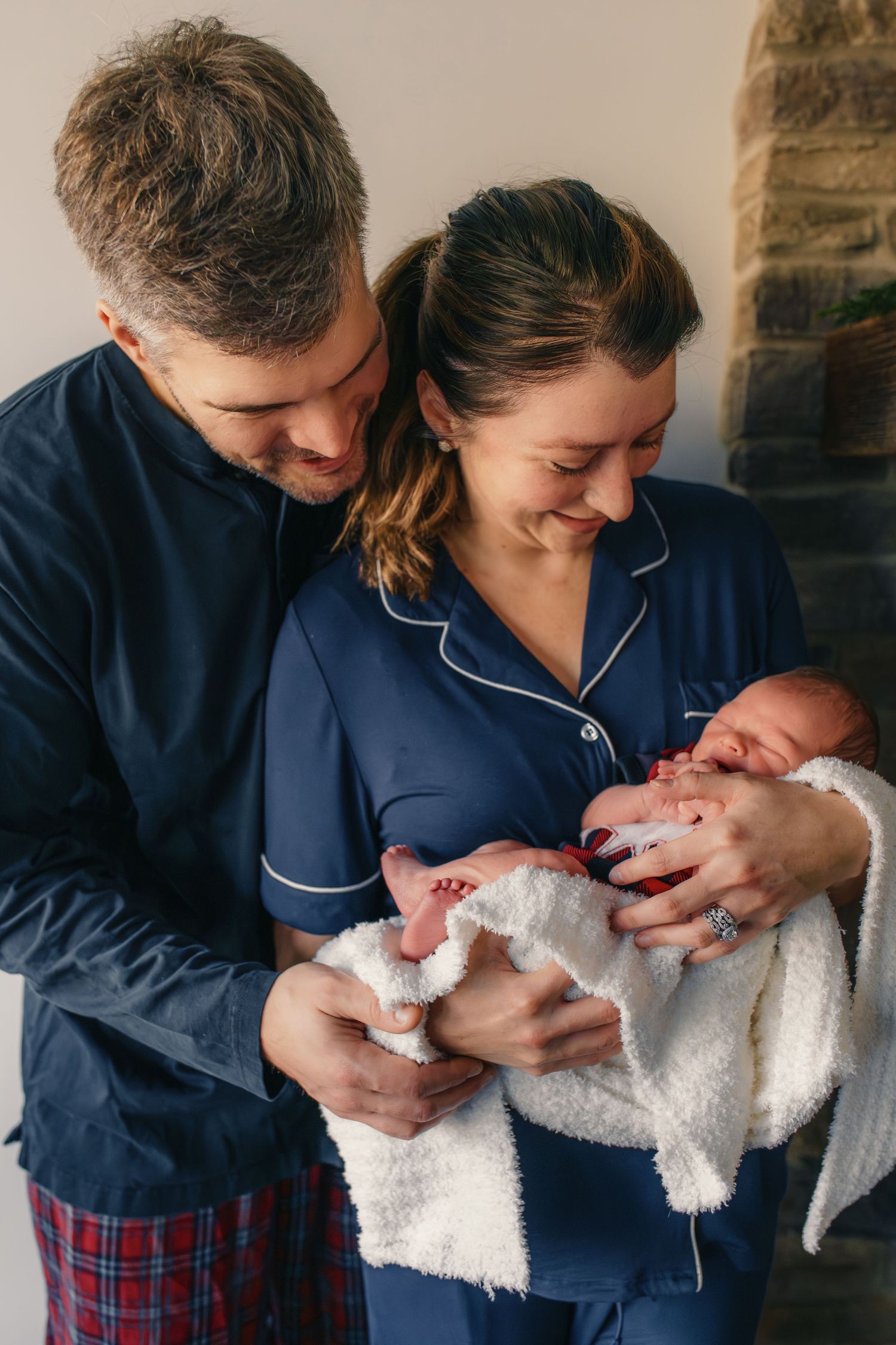 New parents in pajamas sharing intimate moment with their newborn.