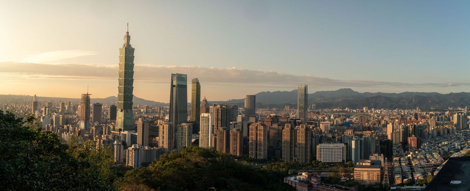 Panoramic cityscape view of urban skyline with mountains in the background at sunset.