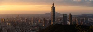 City skyline at dusk with prominent tower silhouetted against an orange sky.