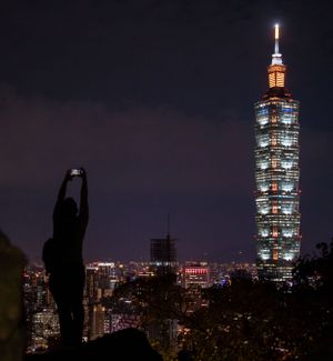 Illuminated Taipei 101 tower standing tall against the night sky with city lights below.