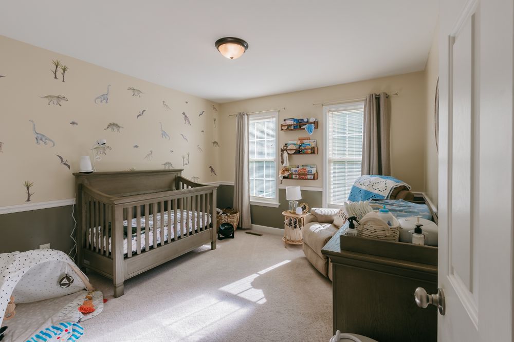 Neutral nursery with grey crib, patterned wallpaper, and built-in shelving near windows.