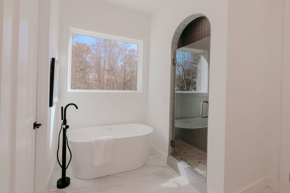 Modern bathroom featuring a freestanding tub and arched doorway.