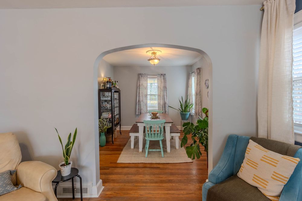 Arched doorway leading to dining area with mint green chairs and houseplants.