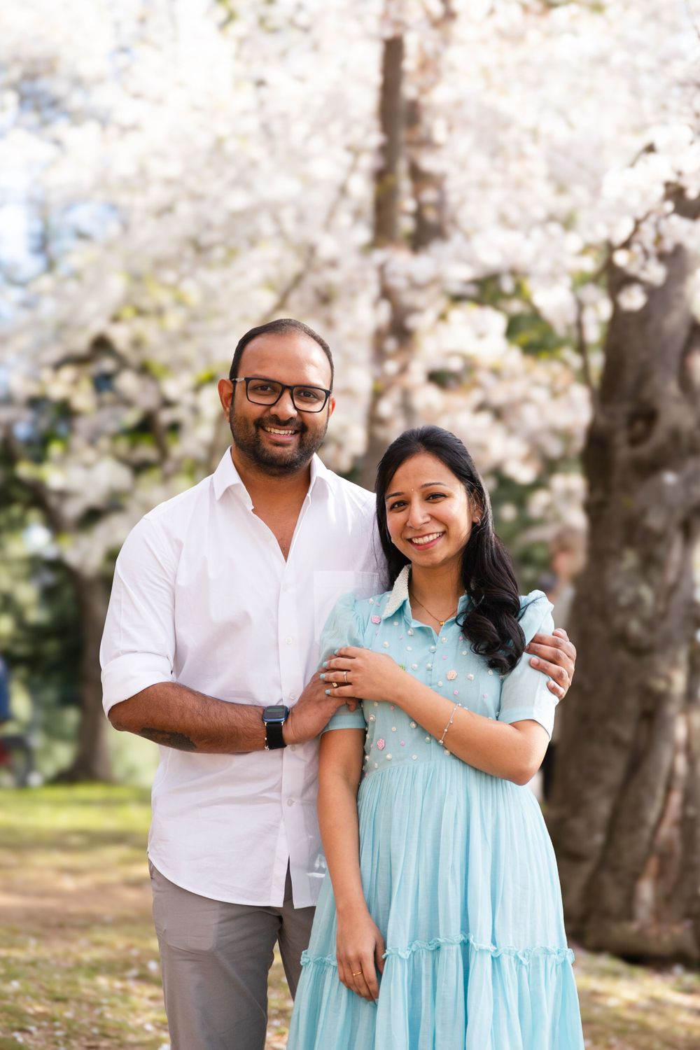 A couple shares tender moments under blooming cherry blossom trees during a spring photo session.