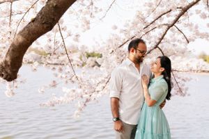 Romantic couple embraces under flowering cherry trees on a bright spring day.