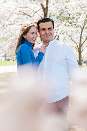 Romantic spring portraits captured under flowering cherry trees with soft lighting.