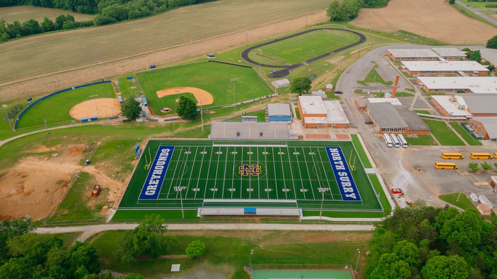 Aerial view of a high school football field and campus facilities from above.