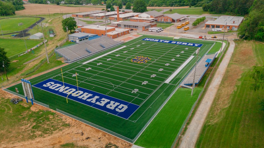 Aerial view of a green football field with EAGLESEYES text painted on the artificial turf.