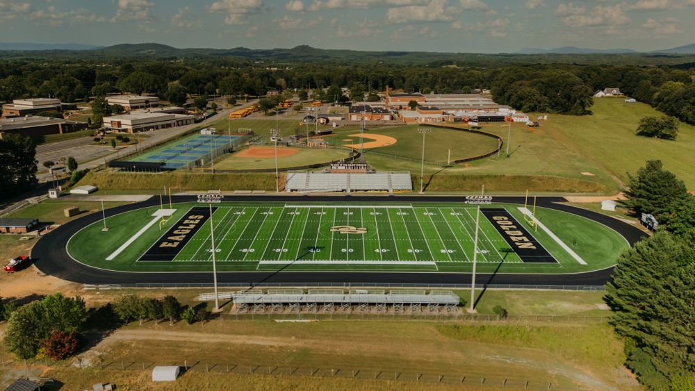 Aerial photograph of a high school football stadium with track and bleachers surrounded by green landscape.