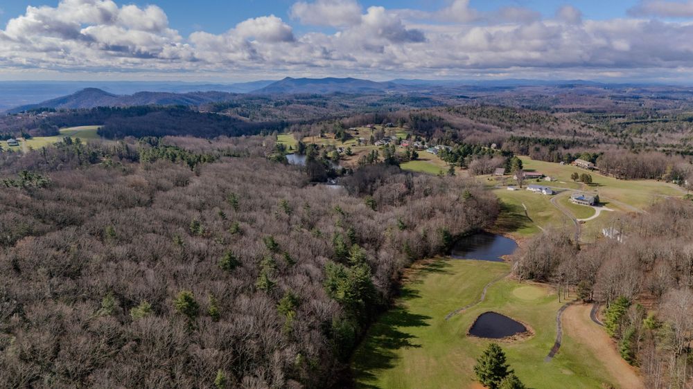 Aerial view of rolling mountains and valleys with scattered homes in early spring.