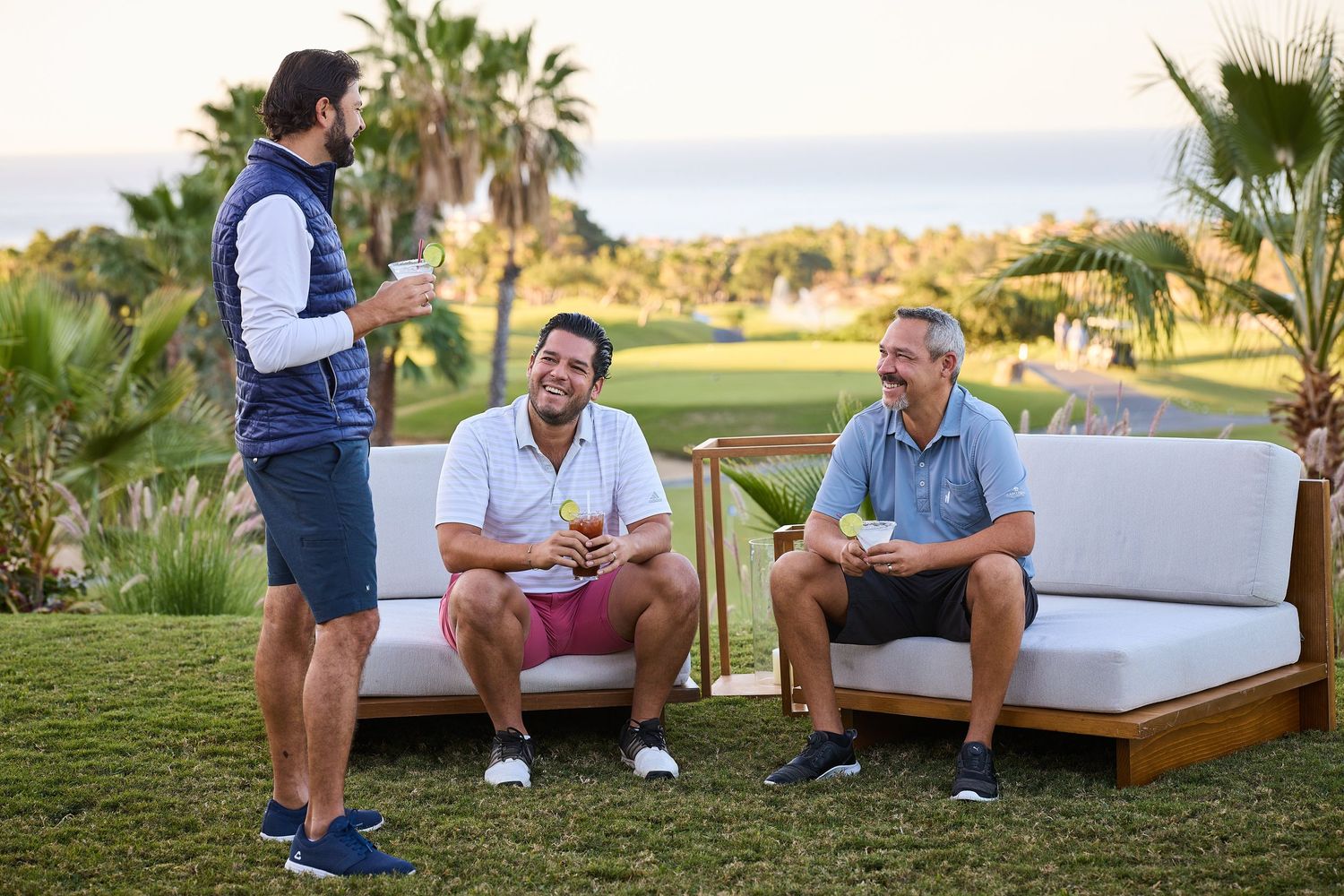 Three people relaxing on outdoor patio furniture at a golf resort.
