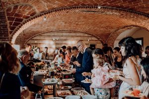 Wedding guests enjoying buffet reception dinner under stunning brick vaulted ceiling in rustic venue.