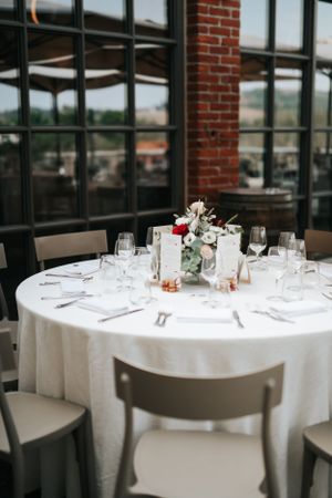 Elegant round wedding reception table with white linen, crystal glasses, and floral centerpiece in a modern venue.