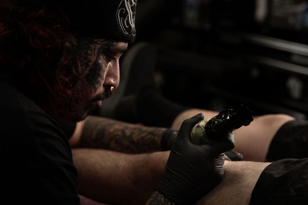 A person wearing boxing gloves strikes a punching bag during an intense workout session in a dimly lit gym.