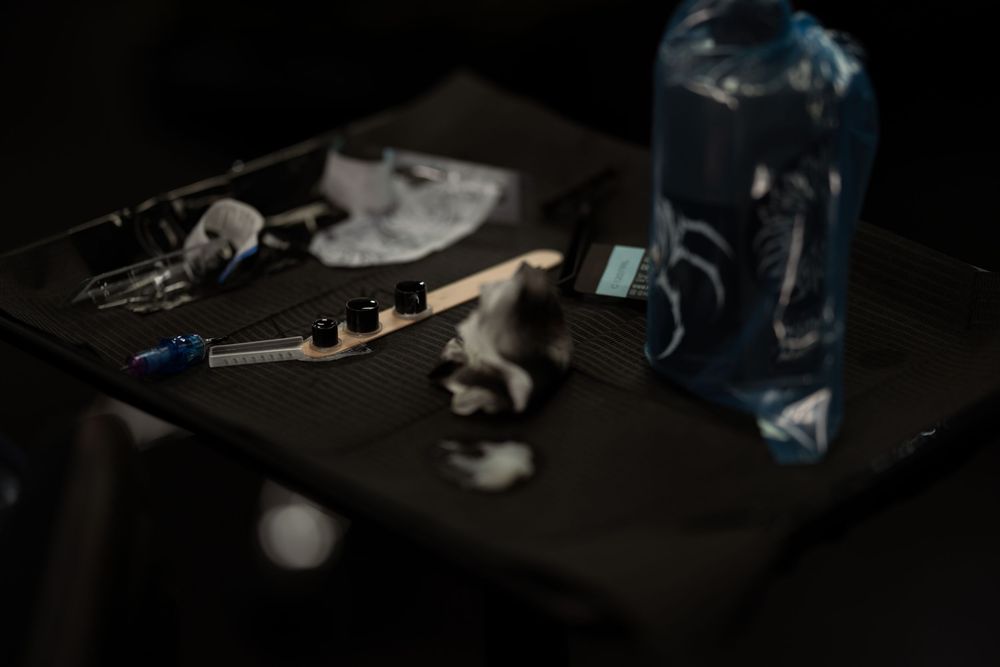 A dark moody still life with keys, photographs and a blue glass bottle on a black surface.