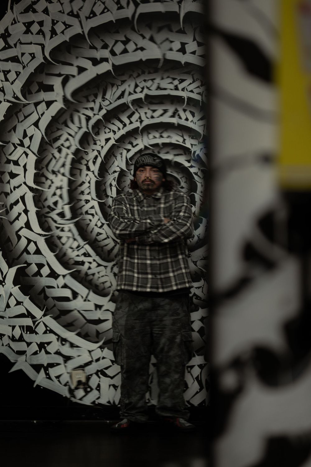 A sequence of photos showing a figure against a black and white spiral graffiti wall background.