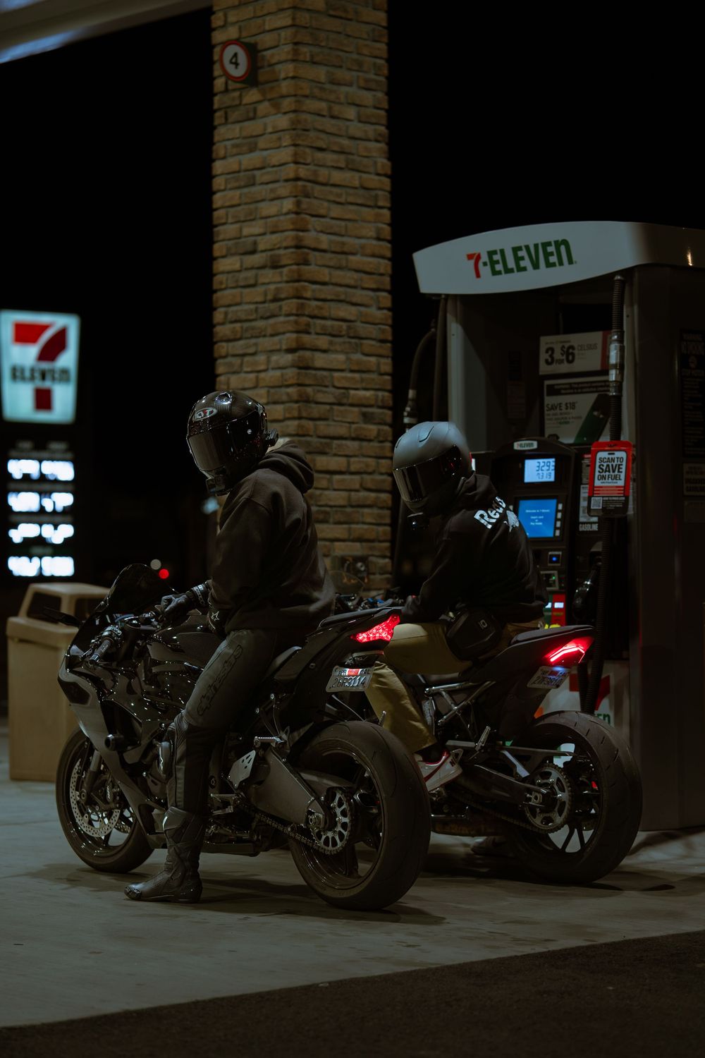 Several motorcycles parked in a row outside a 7-Eleven convenience store at night.