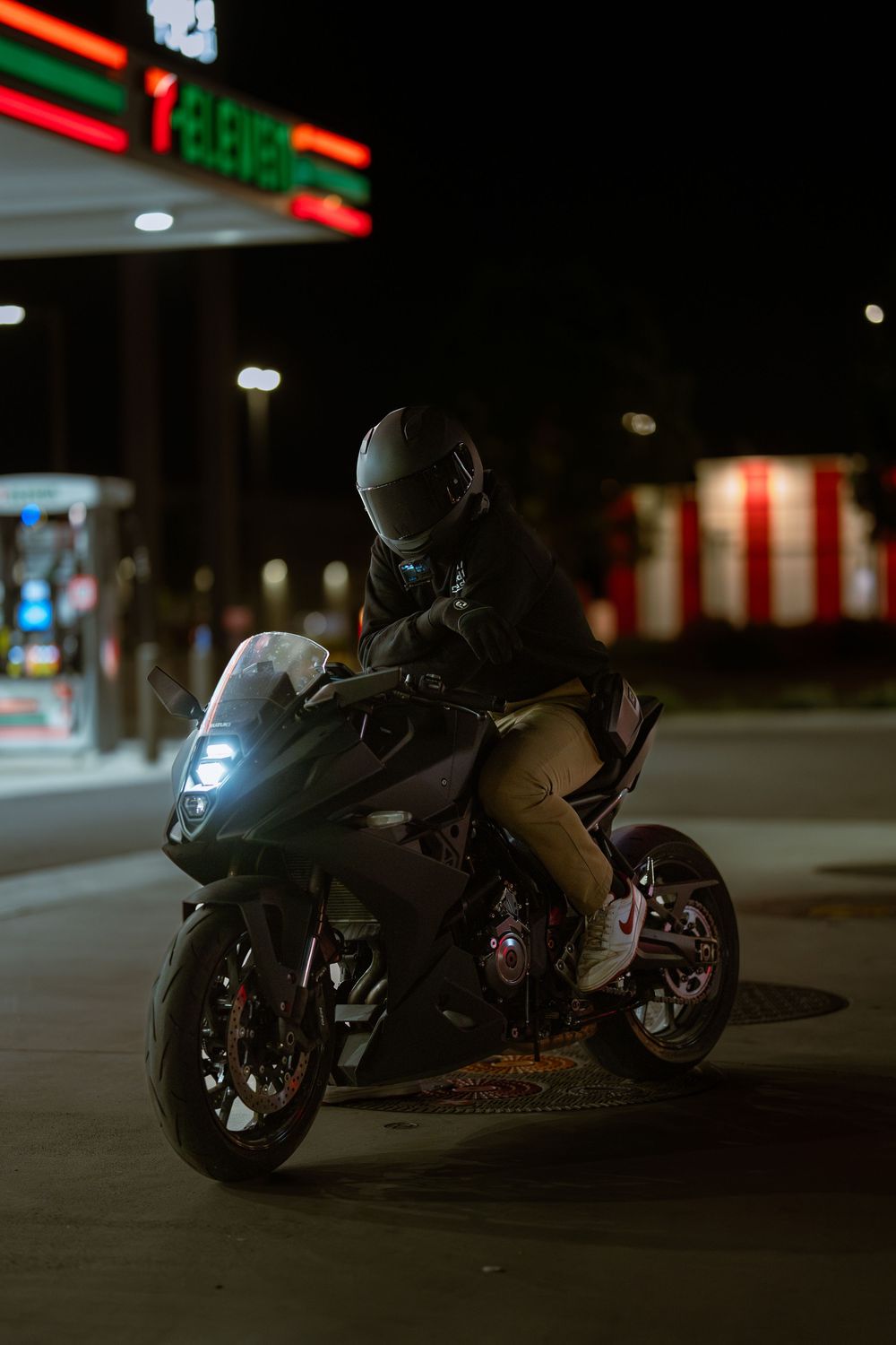 A dark motorcycle parked at night under ambient lighting in a parking lot, showing multiple angles of the same bike.