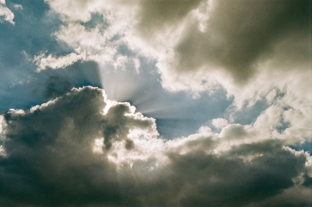 Dramatic cloud formations with sunlight streaming through dark storm clouds in the sky.