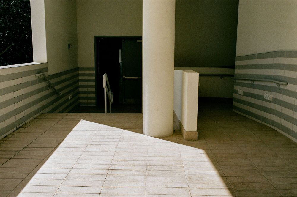 Modern minimalist hallway interior with striped walls and geometric shadows.
