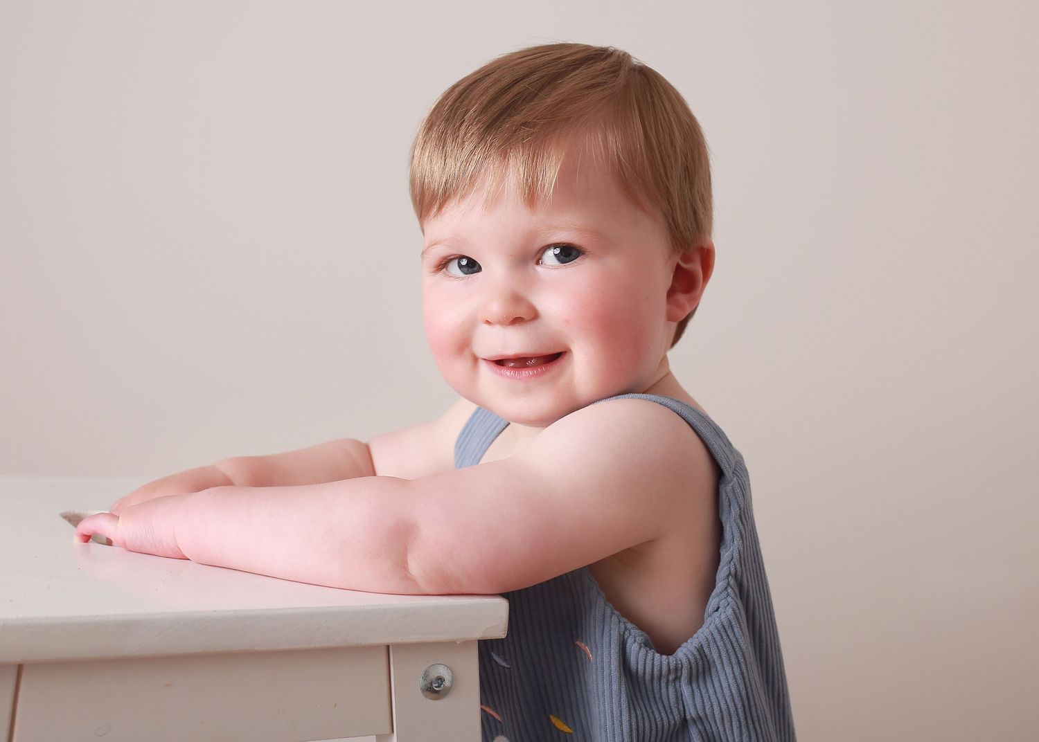 A cheeky 1-year-old flashing a playful smile, capturing their fun and mischievous personality during a joyful  photography session