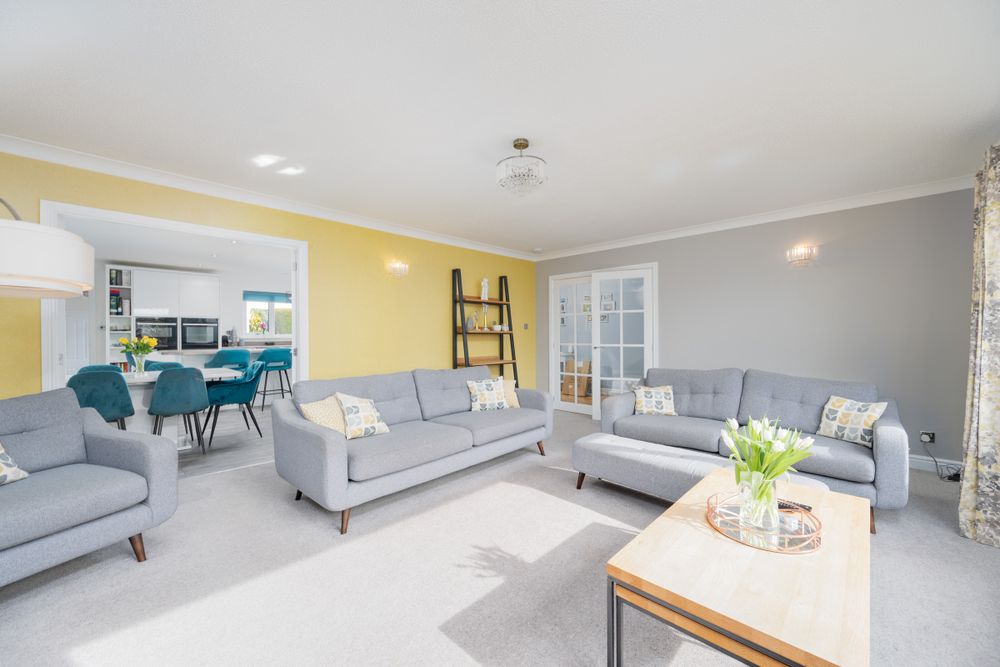 Modern living room interior with gray couches, yellow accent wall, and open floor plan design features natural lighting.