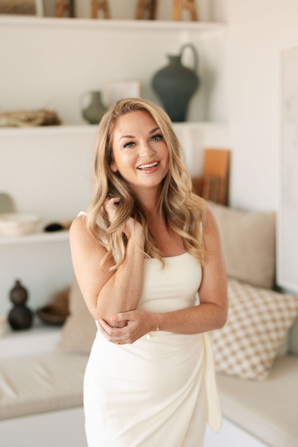 Natural light portrait with decorative shelf styling in background.