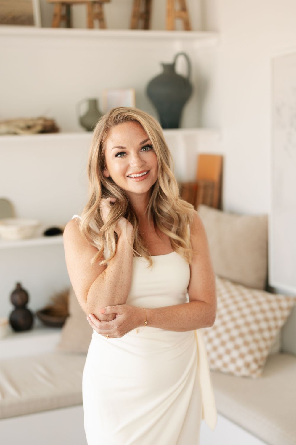 Professional lifestyle portrait in a bright interior space with white decor and decorative shelving.
